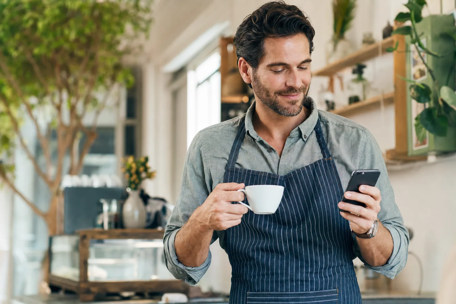 Titolare di un locale sereno con un caffè mentre il chatbot AI risponde ai clienti su WhatsApp
